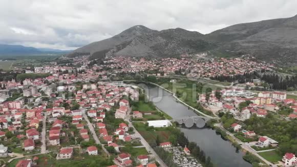 鸟瞰波斯尼亚黑塞哥维那特雷比涅河和历史桥梁欧洲的老城区有山有房子环绕着大里夫视频的预览图