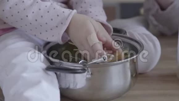 近景小女孩坐在桌子旁帮妈妈煮面条孩子把面条放进锅里这就是视频的预览图