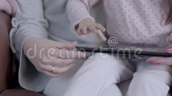 坐在沙发上的祖母母亲和小女儿的手都合上了女孩在敲小器视频的预览图