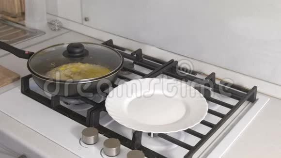 男人手把炒鸡蛋和香肠从煎锅放在煤气炉上放在白色的盘子里视频的预览图