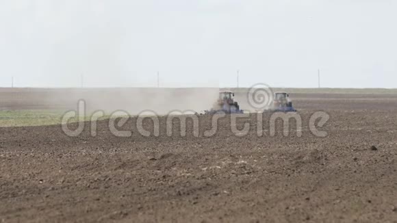 两台拖拉机向相反方向行进的慢镜头和耕地农用拖拉机耕田视频的预览图