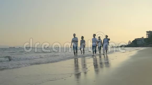 年轻的亚洲成年人在黄昏的海滩上漫步视频的预览图