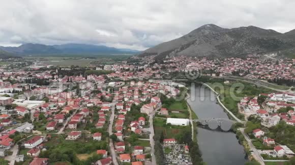 鸟瞰波斯尼亚黑塞哥维那特雷比涅河和历史桥梁欧洲的老城区有山有房子环绕着大里夫视频的预览图
