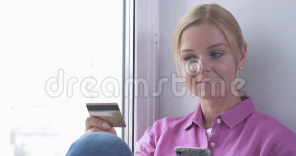 网上购物时微笑的女人手里拿着信用卡的画像视频的预览图