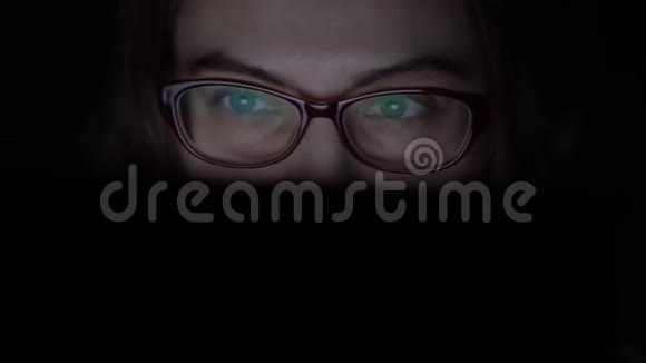 戴眼镜的年轻女孩在晚上用一台移动电脑躺在家里的床上进行在线购买孤立光视频的预览图