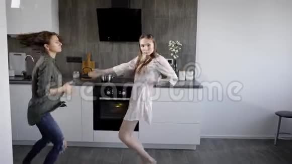 两位年轻的祖先在厨房里跳着充满活力的音乐有趣的女人正在四处闲逛视频的预览图