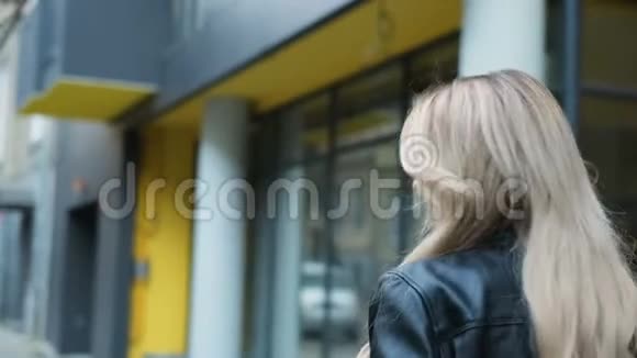 一个迷人的微笑着的时髦女孩的波特莱尔走在街上转向相机和微笑年轻人的户外画像视频的预览图
