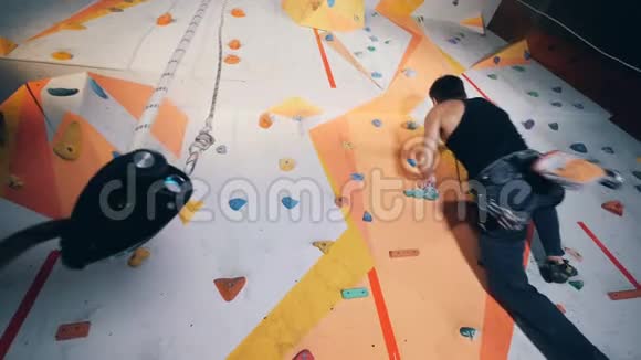 专业攀岩者训练在墙上底部视野视频的预览图