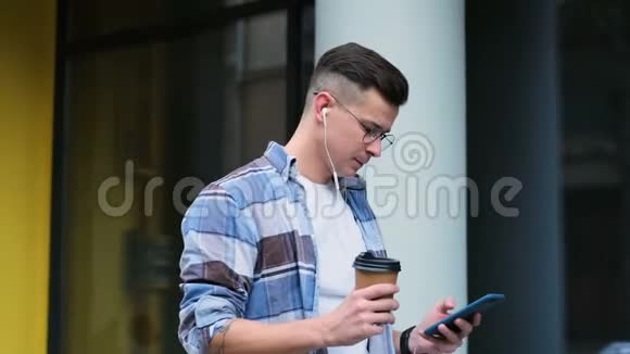 英俊的年轻人在智能手机上交流微笑自信有智能手机喝咖啡的男人的肖像视频的预览图