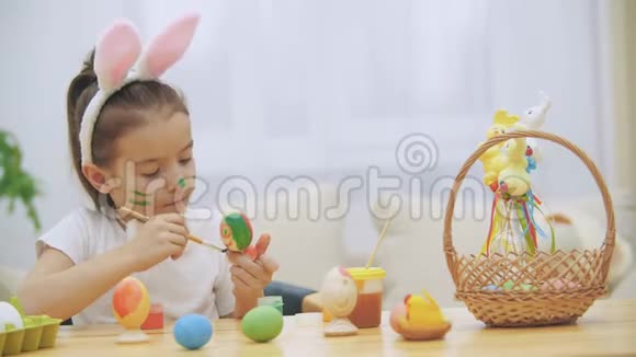 漂亮可爱的女孩正在有趣地画一个复活节彩蛋可爱的女孩正在给鸡蛋上色有美女的女孩视频的预览图