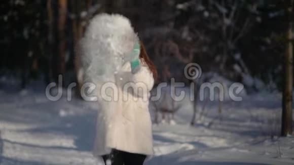 在冬天的森林里阳光明媚的一天年轻的女人扔雪大笑起来视频的预览图