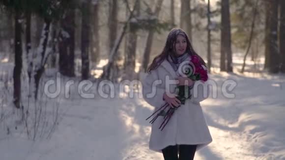 美丽的年轻女子穿过冬天的雪林玫瑰盛开视频的预览图