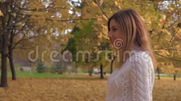 一个女人在秋天的公园里散步的侧景让她的头和微笑视频的预览图