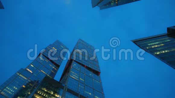 时光流逝由玻璃制成的不寻常形状的现代摩天大楼从底部看日落视频的预览图