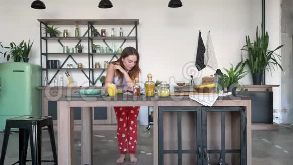 可爱的姜女在厨房里看书跳舞手肘撑在桌子上红头发的女人看着视频的预览图