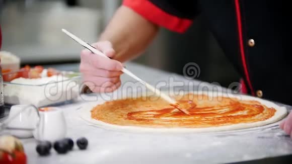 餐厅厨房一个男人用硅胶刷涂在面团上的番茄酱视频的预览图
