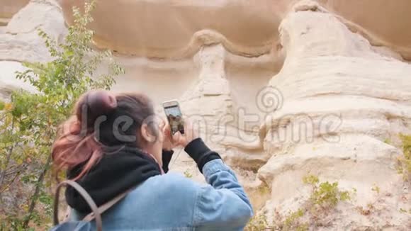 年轻的混合种族旅游女孩使用手机拍摄美丽山脉的照片卡帕多西亚土耳其4K视频的预览图