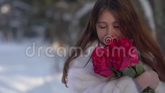 冬天森林里美丽的年轻女子抱着鲜花吸气的肖像视频的预览图