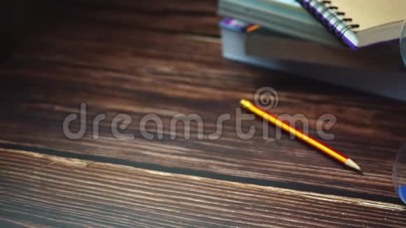 慢动作娃娃沙漏铅笔和书堆放在木桌上视频的预览图