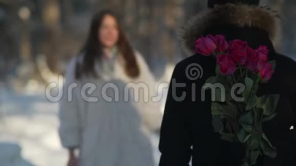 年轻而面目全非的男人身后捧着鲜花等着女朋友视频的预览图