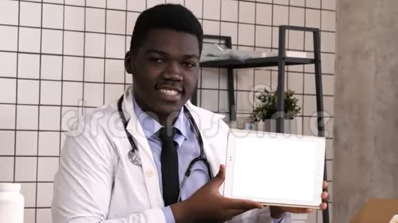 微笑的医生在平板电脑上展示产品白色显示器视频的预览图