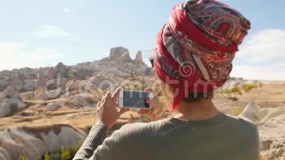 年轻的混合种族旅游女孩使用手机拍摄沙漠谷的照片卡帕多西亚土耳其4K视频的预览图