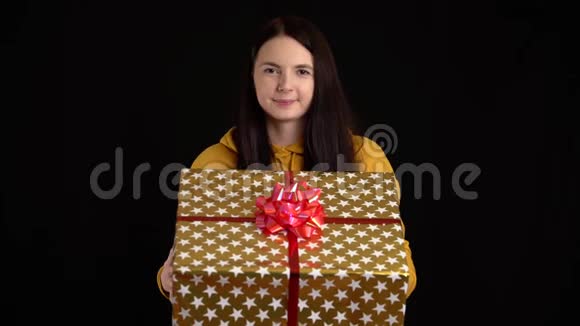 年轻女子在黑色背景上赠送礼品盒带白色丝带的礼品盒祝新年快乐圣诞快乐视频的预览图