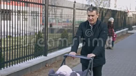 推婴儿车的成熟男人在一个美丽的春天里散步爷爷和孙女视频的预览图