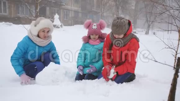 妈妈和两个女儿在冬天堆雪人视频的预览图