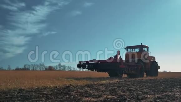 秋天一辆黄色拖拉机在犁地上行驶收割视频的预览图