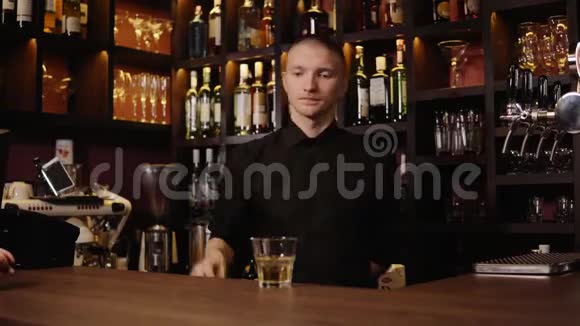 酒吧内部的年轻酒吧服务员把威士忌倒在玻璃里然后拿来给客人视频的预览图
