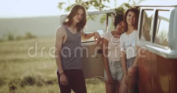一个留着长发的男人和他的两个朋友的女士站在一辆复古巴士旁边在一起度过了美好的时光视频的预览图