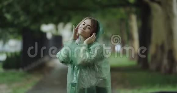 微笑的女人在雨中跳舞穿着绿色的雨衣视频的预览图