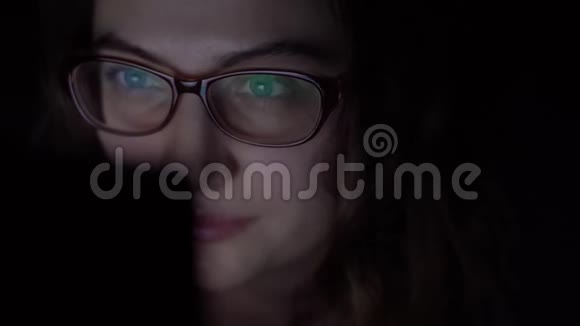 漂亮的小女孩戴着眼镜在家里躺在床上用移动电脑进行网上购物视频的预览图