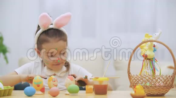 可爱的小女孩真诚地微笑着她拿了一个复活节彩蛋用她的方式展示了她的工作成果视频的预览图
