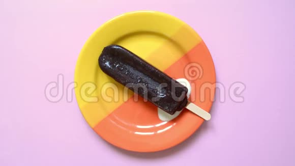 传统巧克力冰淇淋在夏天融化在一个美丽的明亮橙色盘子上柔软的粉红色背景视频的预览图