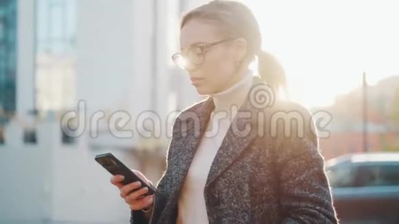 女孩在户外使用手机一个手里拿着智能手机的年轻女人的肖像视频的预览图