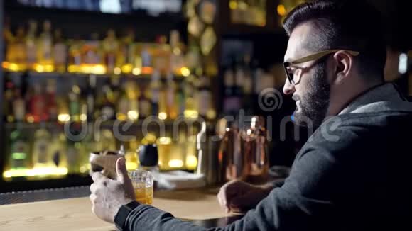 给那个人喝一杯一个在酒吧喝威士忌的男人的特写镜头视频的预览图