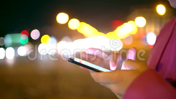 一个年轻的嬉皮士独自站在夜间的街道上在社交媒体上查看他的消息视频的预览图
