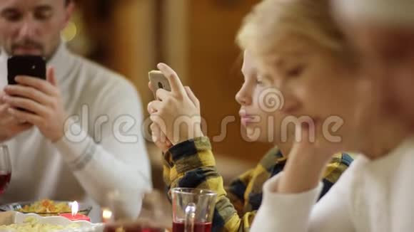 在节日圣诞晚餐期间祖母与其他家庭成员一起在智能手机上上网亲密无间视频的预览图