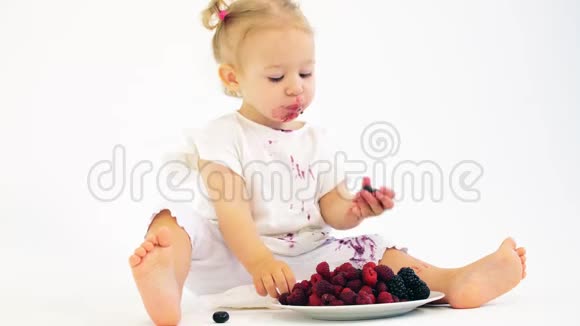 可爱的女婴在白色背景下吃新鲜多汁的浆果视频的预览图