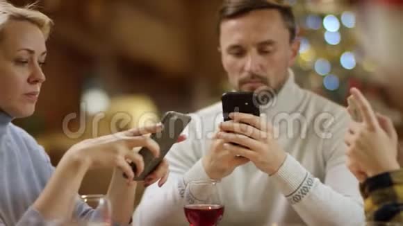 男人女人和小男孩在圣诞满桌的智能手机上上网特写镜头视频的预览图