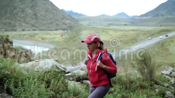 旅行者女孩戴着帽子背着背包爬山人走出画面背景山脉和视频的预览图