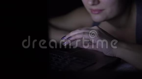 晚上躺在床上的漂亮女人在笔记本电脑键盘上打字特写镜头4K视频的预览图
