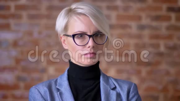 一幅中年金发短发女子戴着眼镜认真观看镜头的肖像背景是布里克肯墙视频的预览图