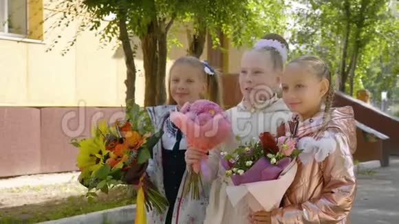 快乐的女学生和鲜花交谈站在学校附近在一起视频的预览图