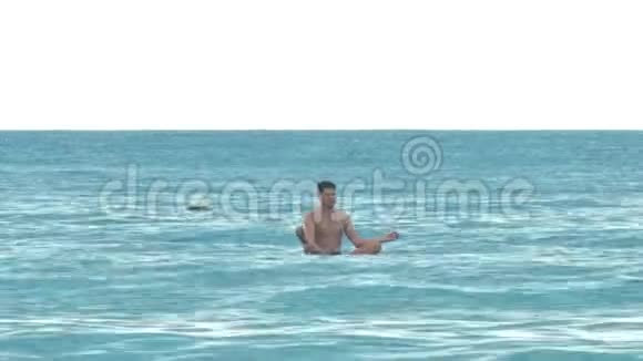 男子坐在瑜伽姿势的桨板上漂洋过海视频的预览图