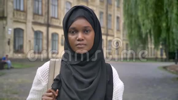 年轻悲伤的非洲穆斯林妇女戴着头巾看着摄像机站在大学附近的公园里压力很大情绪低落视频的预览图