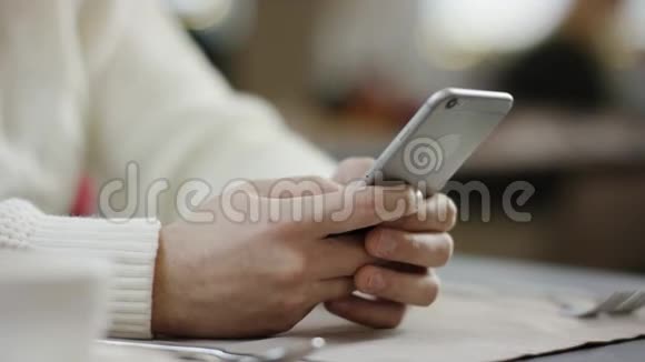 一个成年人在咖啡馆的智能手机上输入信息视频的预览图
