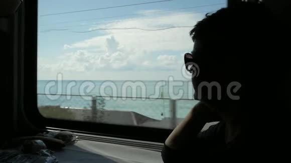 戴墨镜的女人剪影透过火车车厢的窗户看视频的预览图